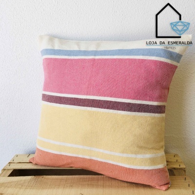 Almofada com riscas coloridas sobre caixa de madeira, parede branca