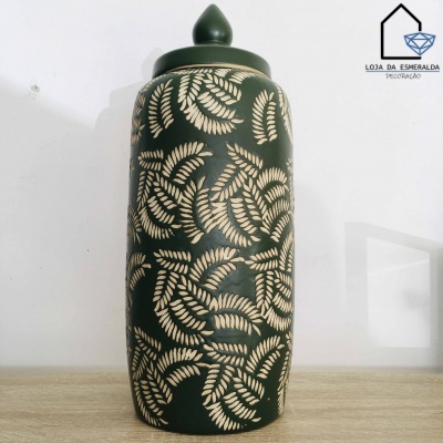 Pote decorativo em cerâmica verde com padrão de folhas bege e tampa, em superfície de madeira clara.