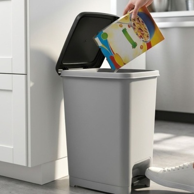 Contentor de lixo cinza com tampa preta aberta numa cozinha