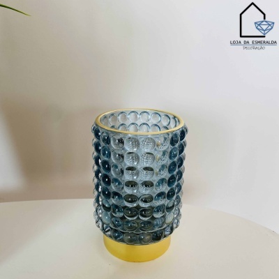 Vaso azul com textura de bolhas e base dourada em superfície branca.