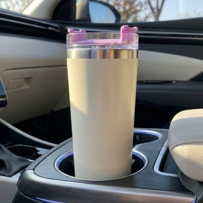 Copo térmico bege com tampa rosa no suporte de copos de carro
