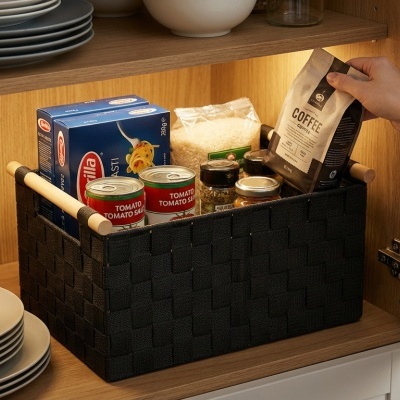 Cesto preto com alças de madeira contendo alimentos dentro de armário de cozinha em madeira clara