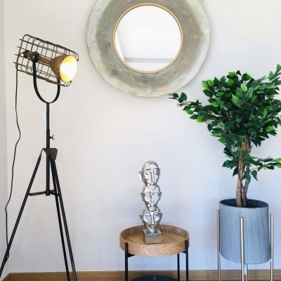 Decoração com candeeiro de pé, espelho redondo, escultura metálica e planta em vaso cinzento
