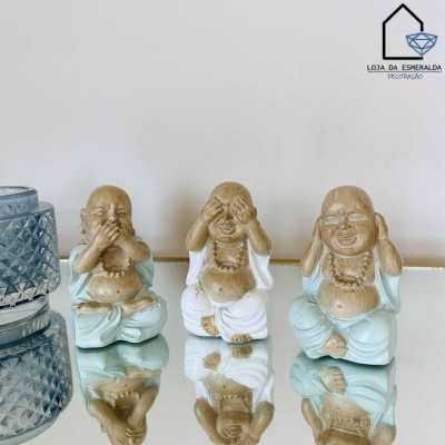 Três estatuetas de Buda sorridente em diferentes posições sentados numa superfície espelhada