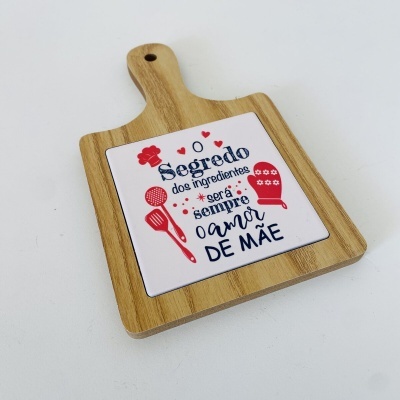 Tábua de cozinha de madeira com azulejo decorativo com texto em português.