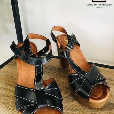 Sandálias pretas em pele com plataforma castanha, fecho de fivela, sobre madeira
