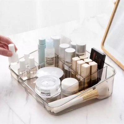 Organizador acrílico transparente com cosméticos e pincéis ao lado de espelho