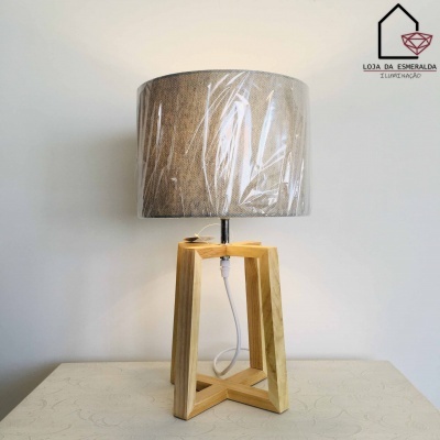 Candeeiro de mesa com base de madeira clara e abajur cinza ainda embalado