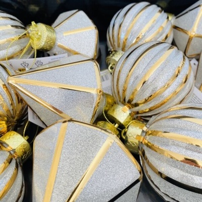 Decorações de Natal prateadas e douradas em formas variadas numa caixa preta