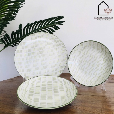 Conjunto de pratos em cerâmica com padrão verde claro e borda verde sobre mesa de madeira