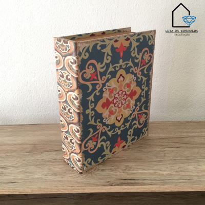 Livro decorativo com padrão floral clássico em várias cores sobre mesa de madeira.