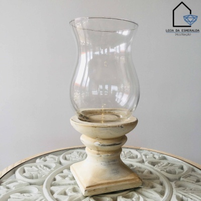 Castiçal de madeira branca envelhecida com copo de vidro transparente sobre superfície branca decorativa