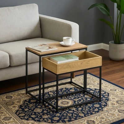 Duas mesas auxiliares de metal preto com tampo e gaveta de madeira natural, ao lado de sofá cinzento, sobre tapete azul com padrão creme, e planta em vaso cinzento