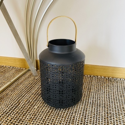Lanterna preta em metal com alça de corda sobre tapete rústico
