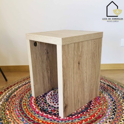 Mesa de apoio em madeira clara sobre tapete multicolorido.