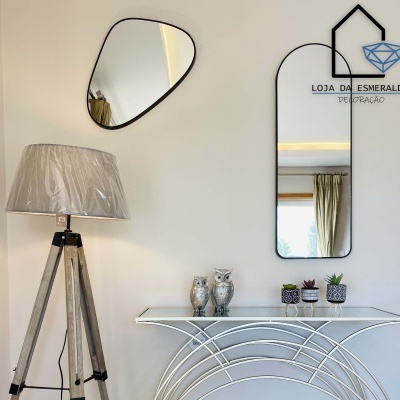 Espaço decorativo com candeeiro, espelhos, consola e decoração com corujas e vasos.