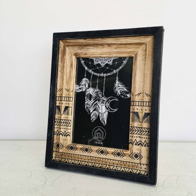 Moldura de madeira decorativa com padrão geométrico e imagem de armadilha de sonhos em preto e branco