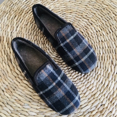 Chinelos tipo mocassim xadrez azul, cinza e castanho sobre superfície trançada clara