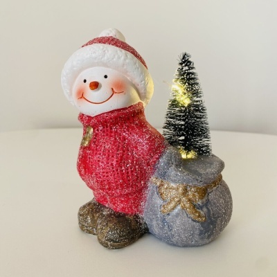 Boneco de neve com camisola vermelha e pequena árvore de Natal iluminada