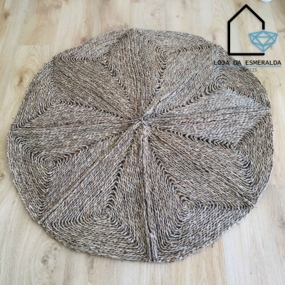 Tapete redondo trançado em fibras naturais bege e castanho sobre chão de madeira clara