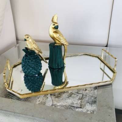 Bandeja dourada espelhada com modelos de pássaros decorativos e abacaxi verde escuro.