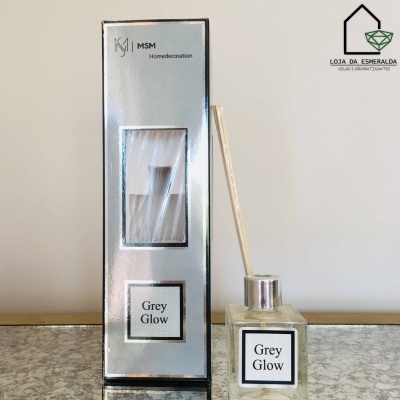Difusor de ambiente Grey Glow em embalagem prateada e frasco de vidro transparente com palitos de madeira