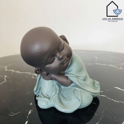 Figurinha decorativa de bebé com túnica azul clara em superfície preta