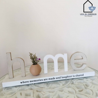 Decoração de mesa com palavra 'home' em vidro e base com texto em inglês.