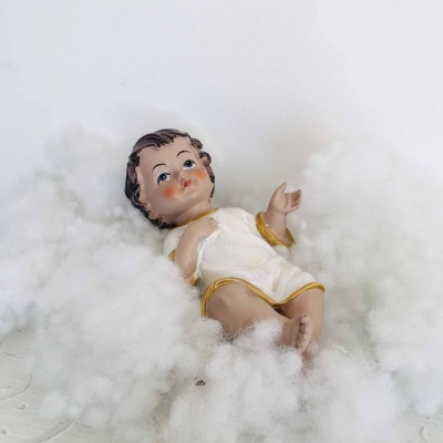 Figura de Jesus menino em túnica branca com bordas douradas sobre algodão branco