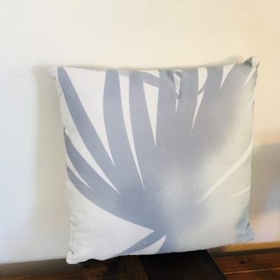 Almofada quadrada cinzenta e branca com padrão abstrato em fundo branco