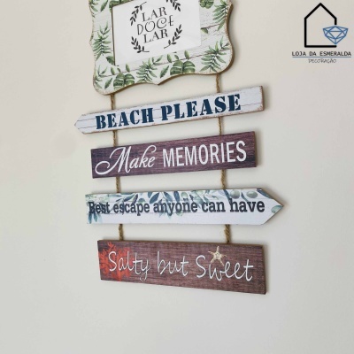 Placa decorativa de madeira com textos em português e inglês pendurada numa parede branca
