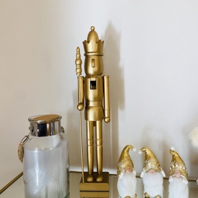 Estátua dourada de soldado de natal, três duendes pequenos dourados, frasco de vidro com tampa metálica sobre espelho