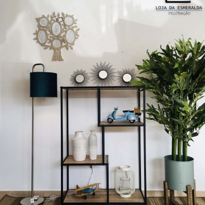 Estante decorativa preta com prateleiras de madeira clara e objetos decorativos, planta verde em vaso cinza e luminária de pé preta