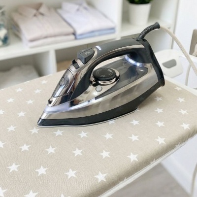 Ferro de engomar elétrico preto e prateado numa tábua de passar com estrelas brancas