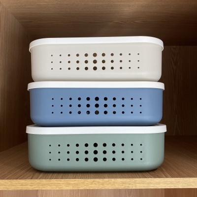 Três caixas organizadoras coloridas com tampas brancas em prateleira de madeira