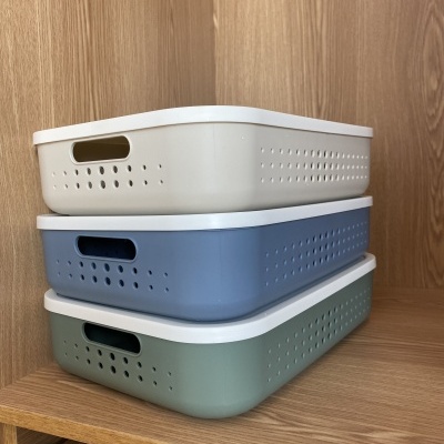 Três caixas organizadoras de plástico empilhadas em prateleira de madeira