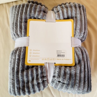 Manta cinza canelada com embalagem branca e etiquetas visíveis