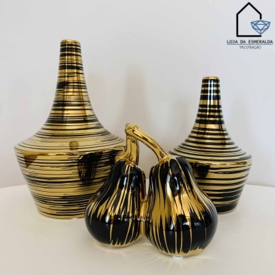 Conjunto de cerâmica com duas garrafas listradas em preto e dourado e duas cenouras douradas e pretas sobre superfície branca