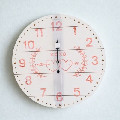 Relógio de parede redondo branco com números vermelhos e corações desenhados
