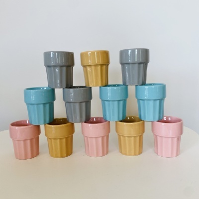 Doze vasos pequenos de cerâmica brilhante em várias cores empilhados