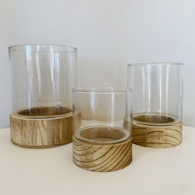 Três copos de vidro com bases de madeira em diferentes tamanhos num fundo branco