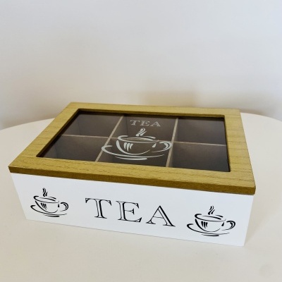 Caixa de chá branca com tampa em madeira clara e visor de vidro, decorada com chávenas e texto TEA