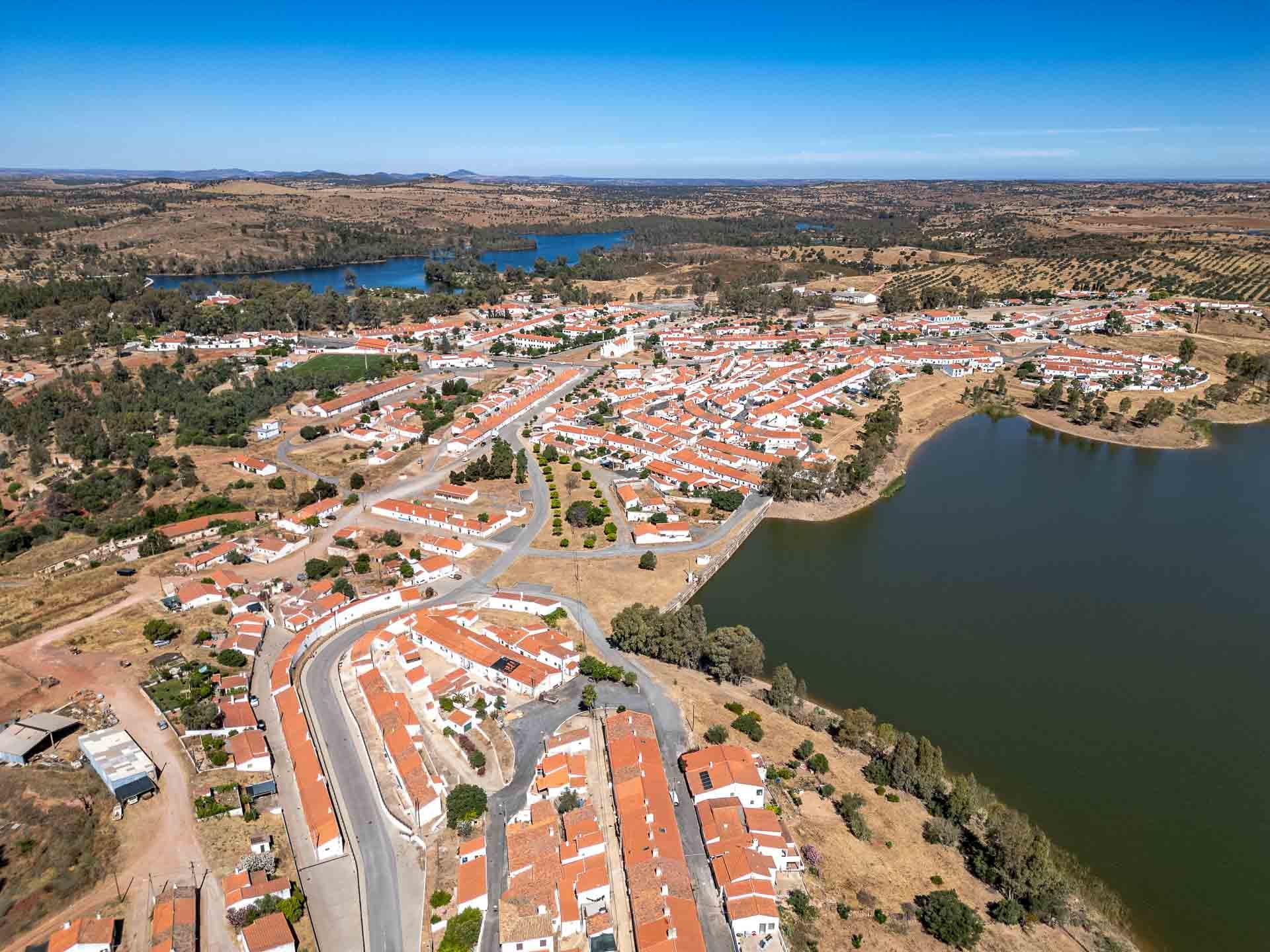 Vista aérea de vila com casas de telhados vermelhos junto a lago