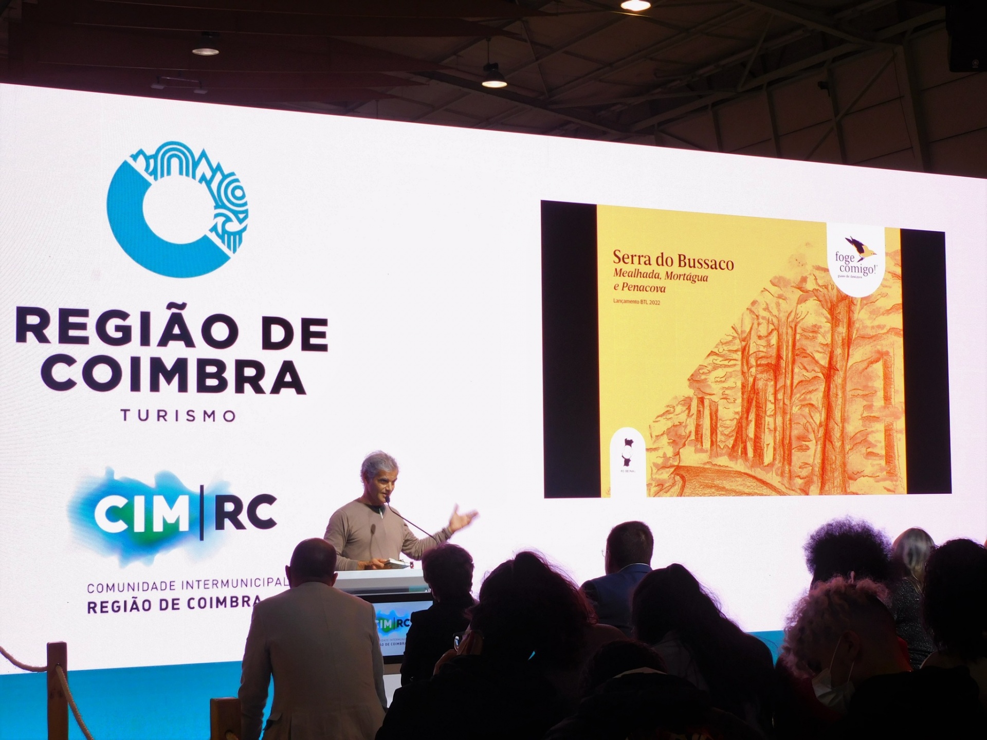 Apresentação em evento com ecrã mostrando logo Região de Coimbra e imagem Serra do Bussaco