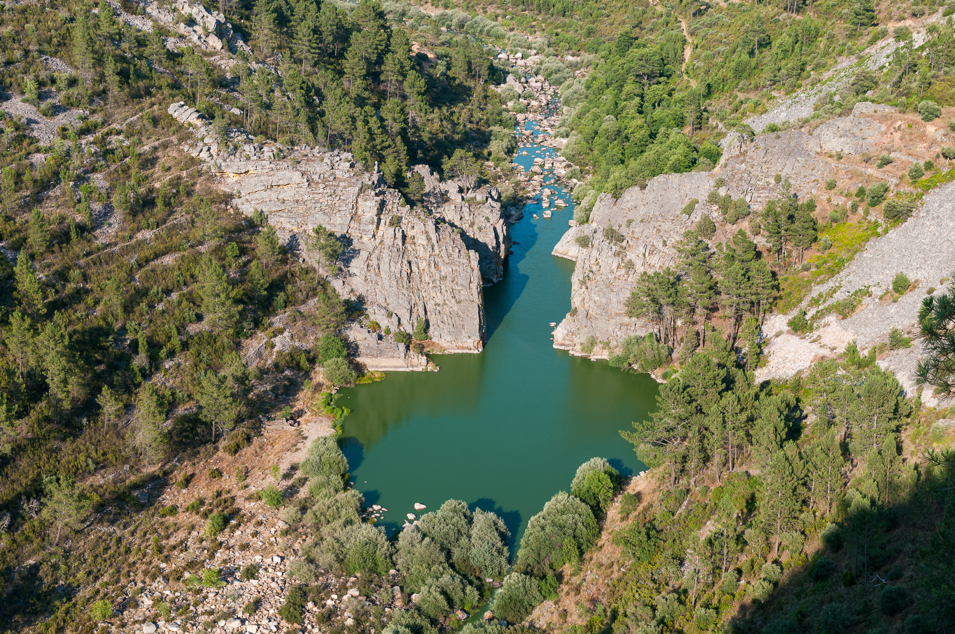 Rio verde entre falésias rochosas e floresta densa visto de cima