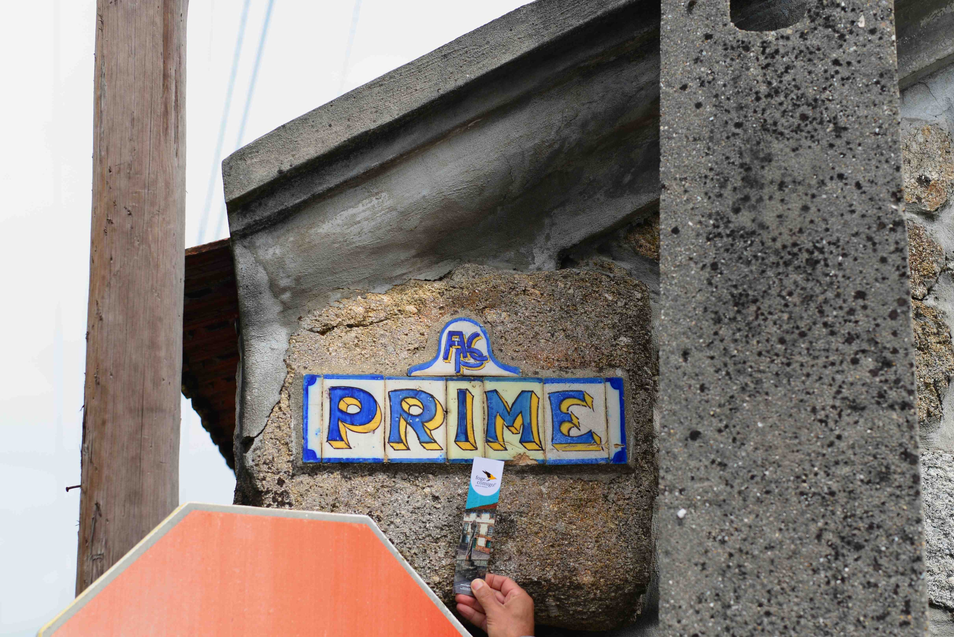 Placa de azulejos com a palavra PRIME em parede rústica com mão a segurar marcador de páginas