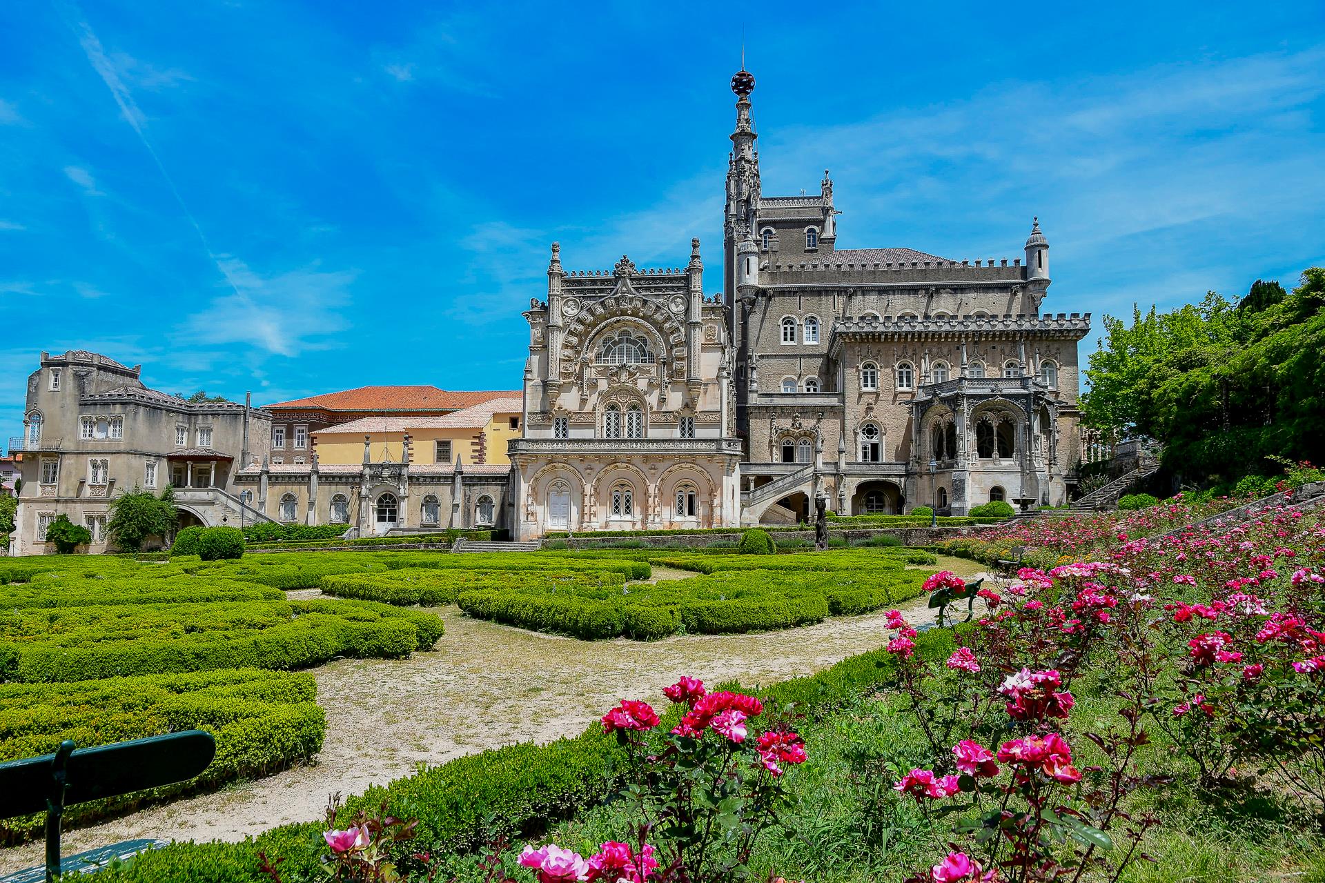 Palácio histórico com jardins floridos e céu azul