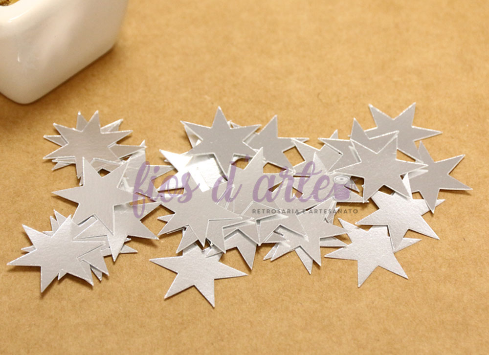 Estrelas prateadas recortadas em papel sobre superfície castanha