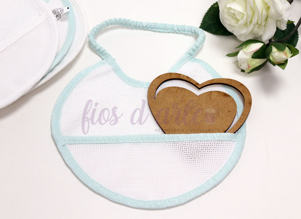 Babete redonda plastificada para bordar ponto cruz Babete redonda branca com bordas azuis claras e molde coração de madeira