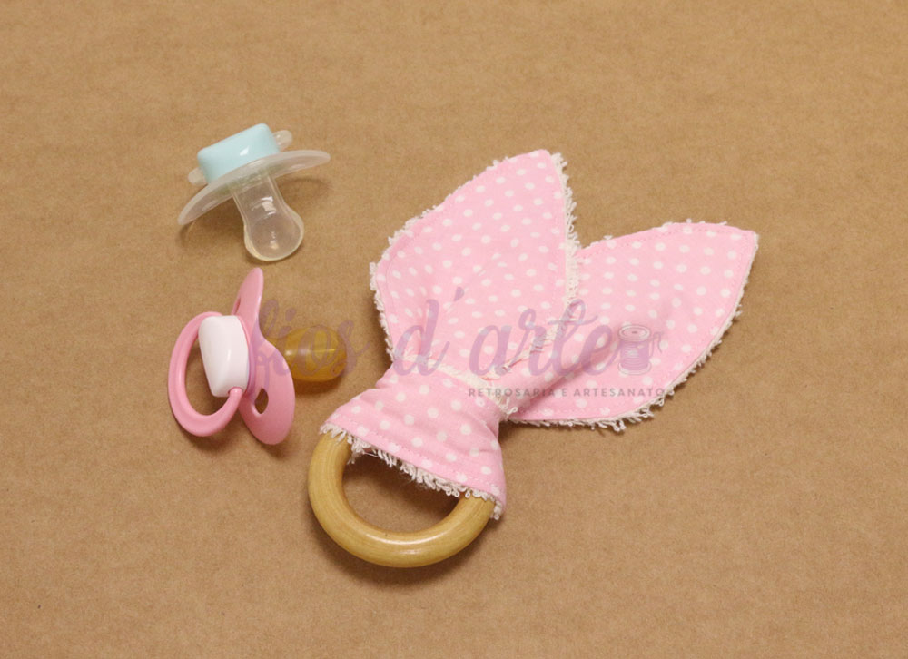 Chupetas azul e rosa e mordedor de madeira com tecido rosa de bolinhas brancas